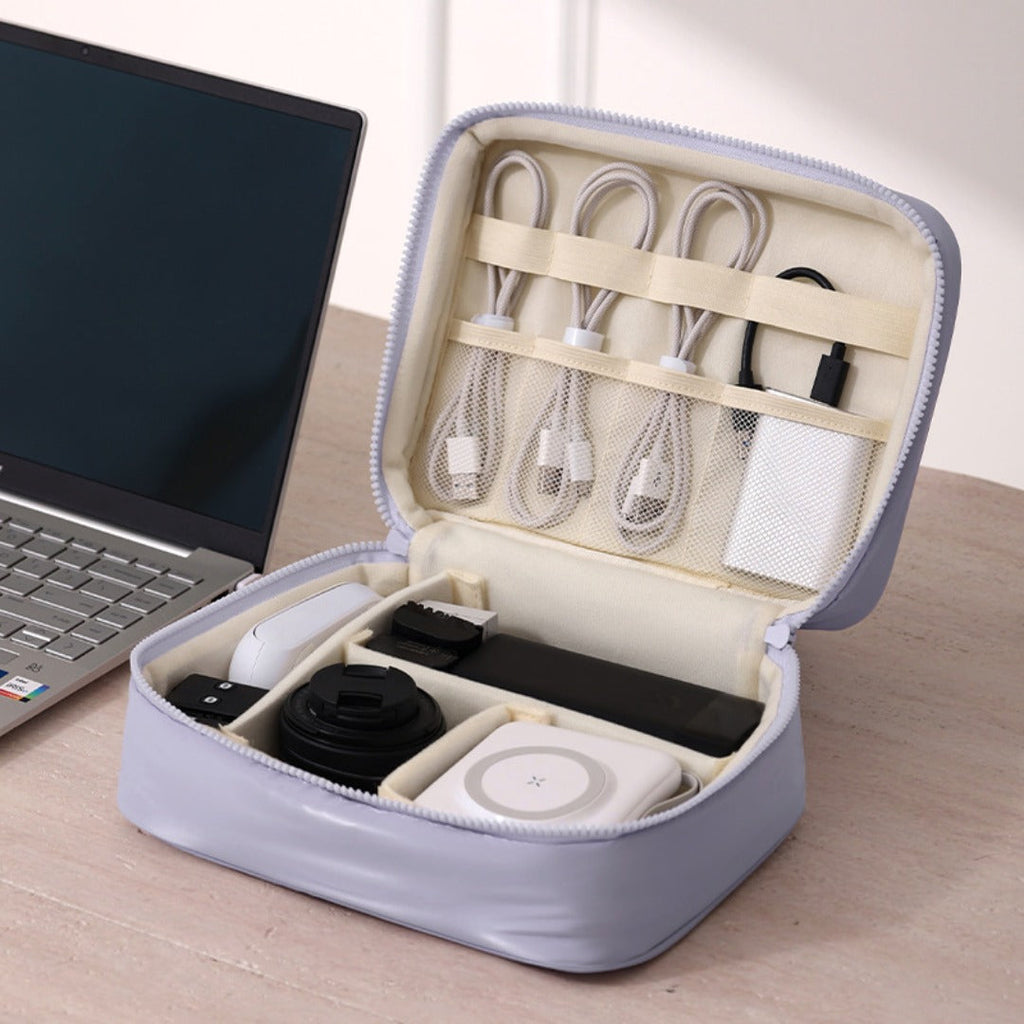 Open lavender travel cable organizer holding white cords, plugs and charging accessories beside a laptop.