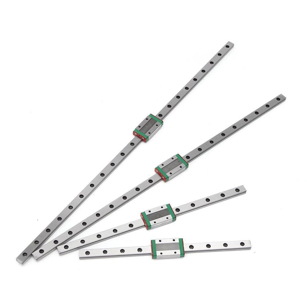 Four silver miniature linear guide rails with green-and-gray sliding blocks arranged on a white background.