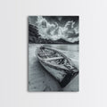 Black-and-white canvas print of an empty wooden rowboat on a shore beneath dramatic clouds.