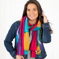 Smiling woman wearing a bright multicolored scarf over a denim jacket.