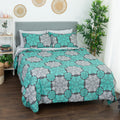Bed dressed in a turquoise, gray and white floral-pattern comforter with matching pillows.