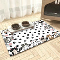 Cartoon cat and paw-print floor mat beneath two pet bowls beside a covered cat litter area.