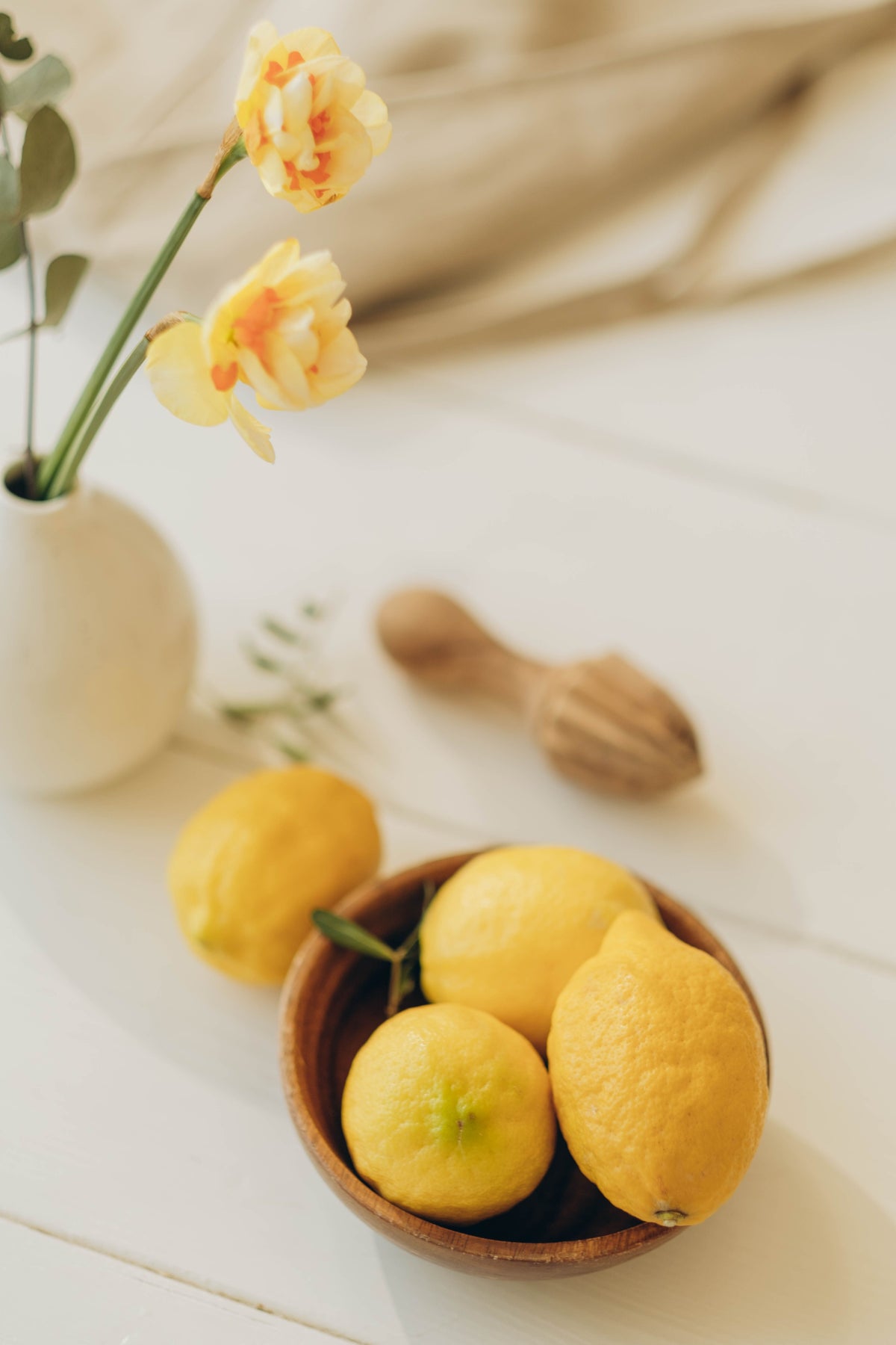 Sunlit still life with bright lemons, yellow flowers and natural home details