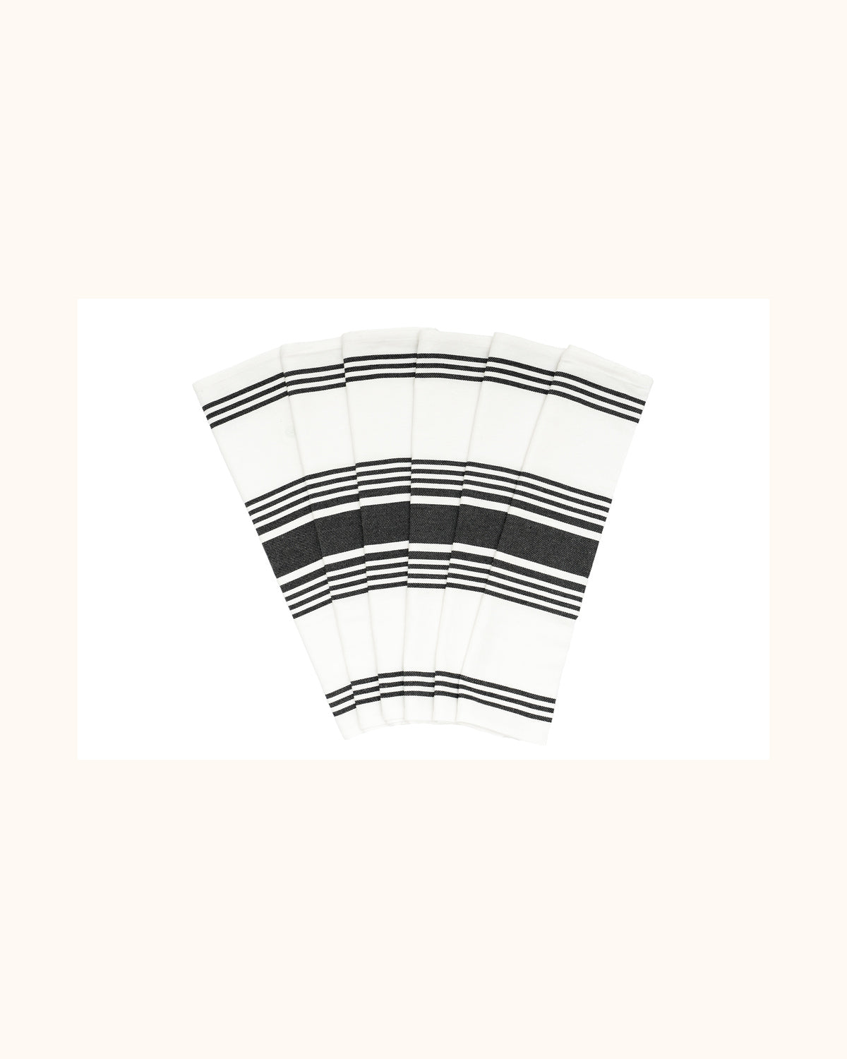 Six white striped cotton kitchen towels arranged in a fan on a warm ivory background.
