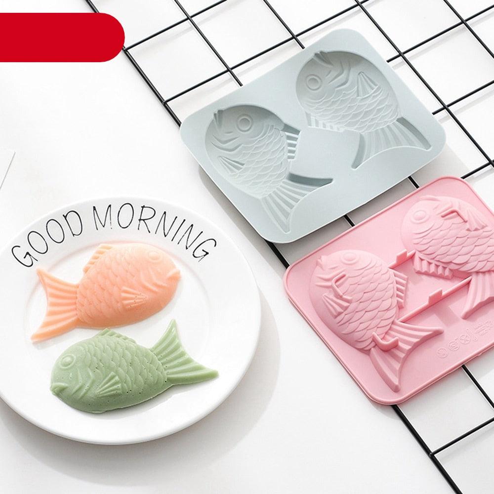 Gray and pink fish-shaped silicone molds beside molded fish-shaped treats on a plate.